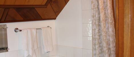 Un baño con techo de madera, un inodoro, un lavabo y una cortina de ducha.