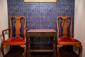Dos sillas de madera con cojines rojos y una pequeña mesa de madera en el centro.