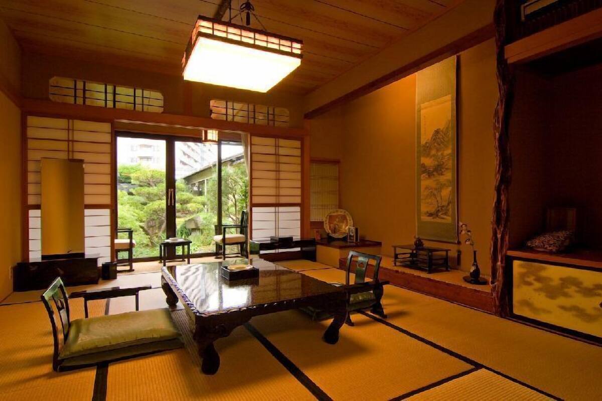 Um quarto japonês tradicional, com piso de tatame, uma mesa baixa e portas deslizantes.