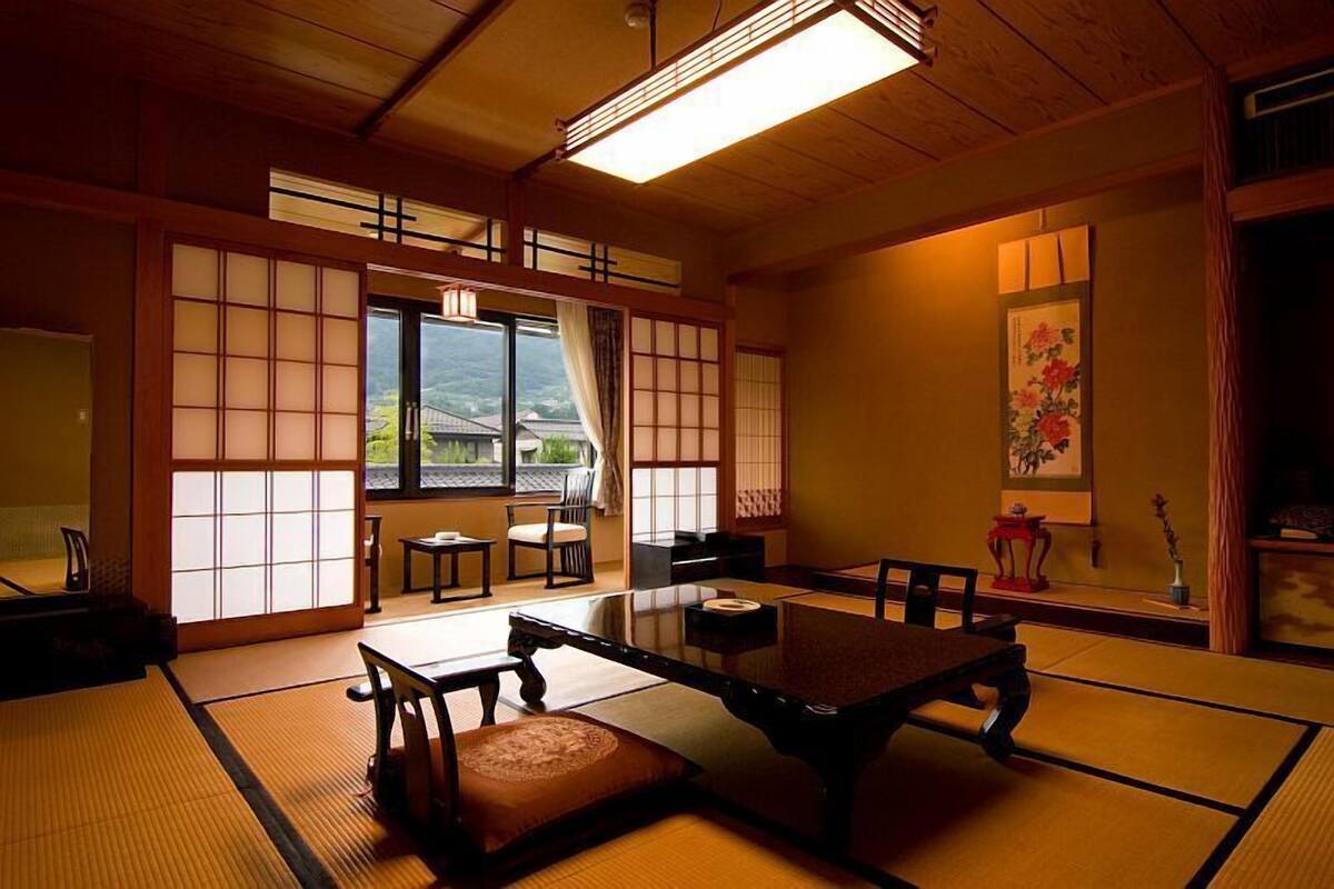 Um quarto japonês tradicional com tatames, uma mesa baixa e portas deslizantes.