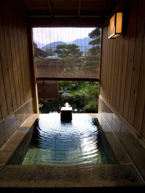 Un onsen japonais traditionnel offrant une vue sur un paysage montagneux à travers un paravent en bois.