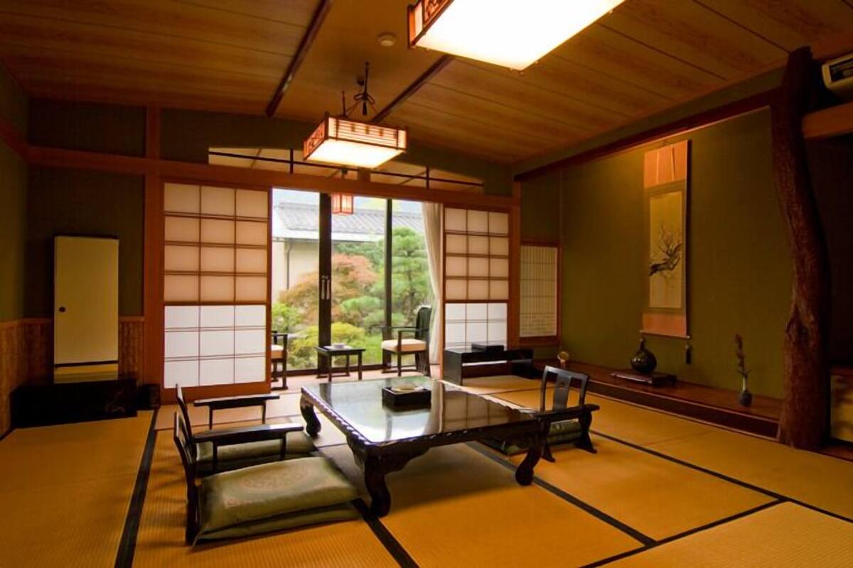 Um quarto japonês tradicional com tatames, uma mesa baixa e portas deslizantes.