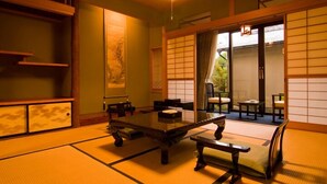 Una habitación japonesa tradicional con suelo de tatami, una mesita baja y puertas correderas.