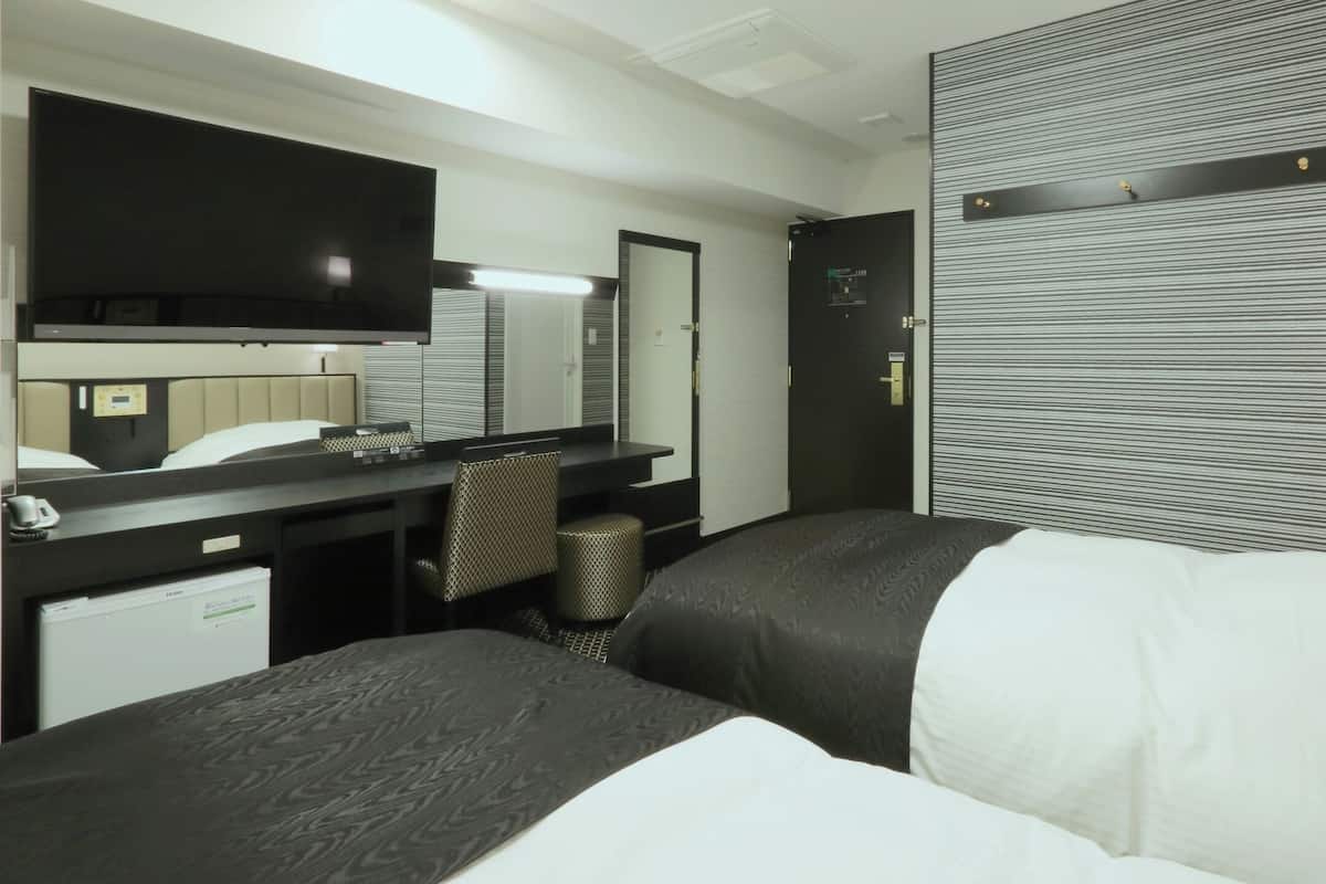 Una habitación de hotel con una cama, un escritorio, una silla, un espejo y una pared con estampado a rayas.
