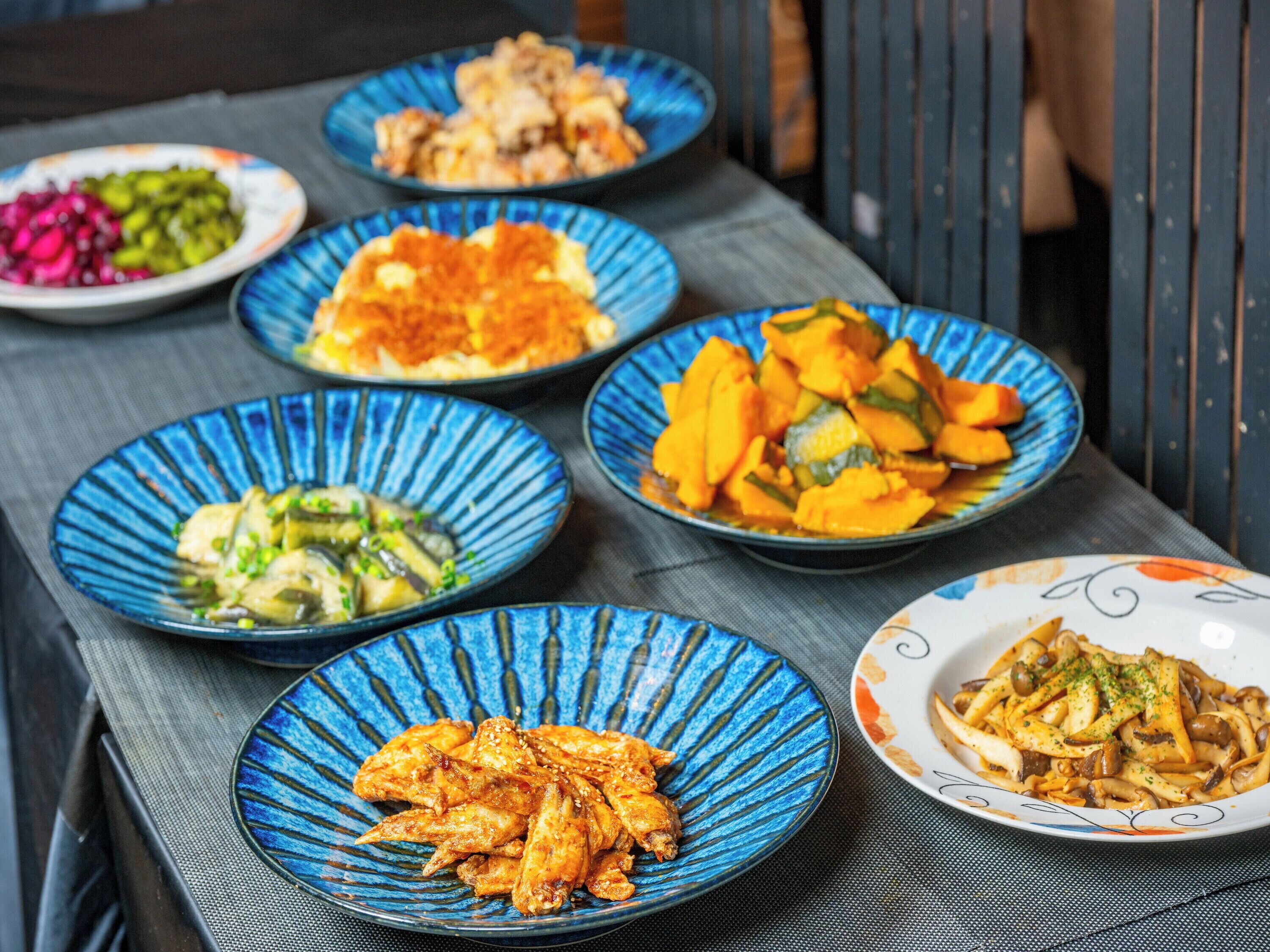 Een tafel met diverse gerechten op blauwe borden.