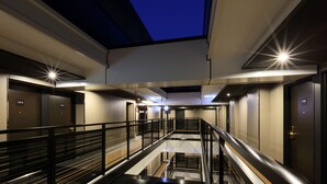 Un hôtel moderne avec un intérieur contemporain, de nombreux étages, des rampes en verre et un atrium central.