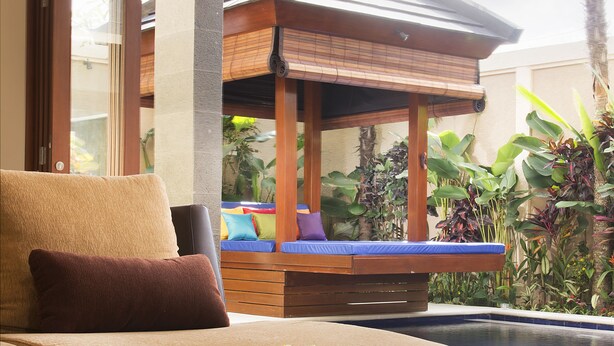 A modern lounge area with a sofa and a poolside view. - The Oasis Retreat Seminyak (Seminyak)