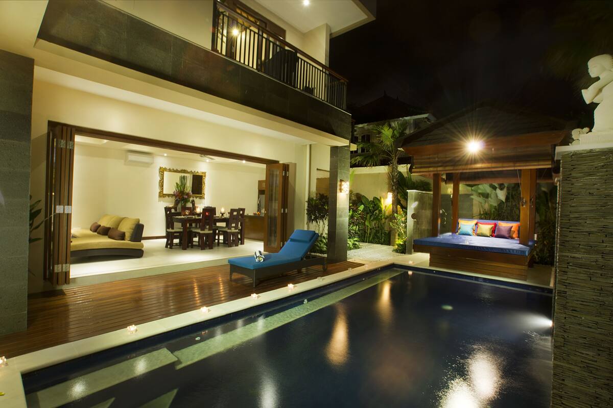 A modern two-story house with a swimming pool, a dining area, and a balcony.