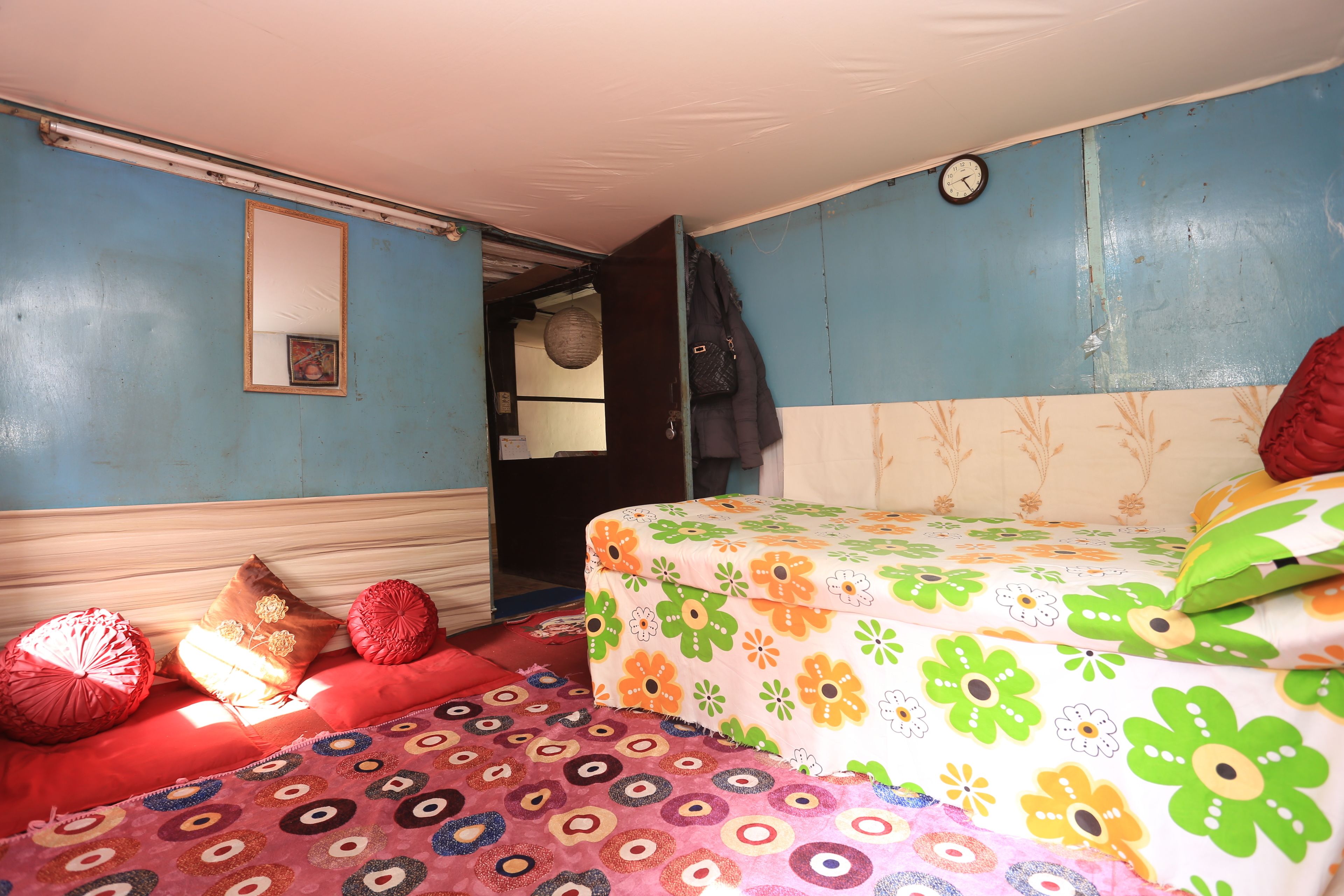 Une pièce avec un lit recouvert d’une couvre-lit à motifs floraux, un canapé rouge et un tapis à motifs.
