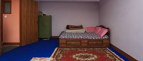 A bedroom with a bed, a wardrobe, a green cabinet, and a red carpet.