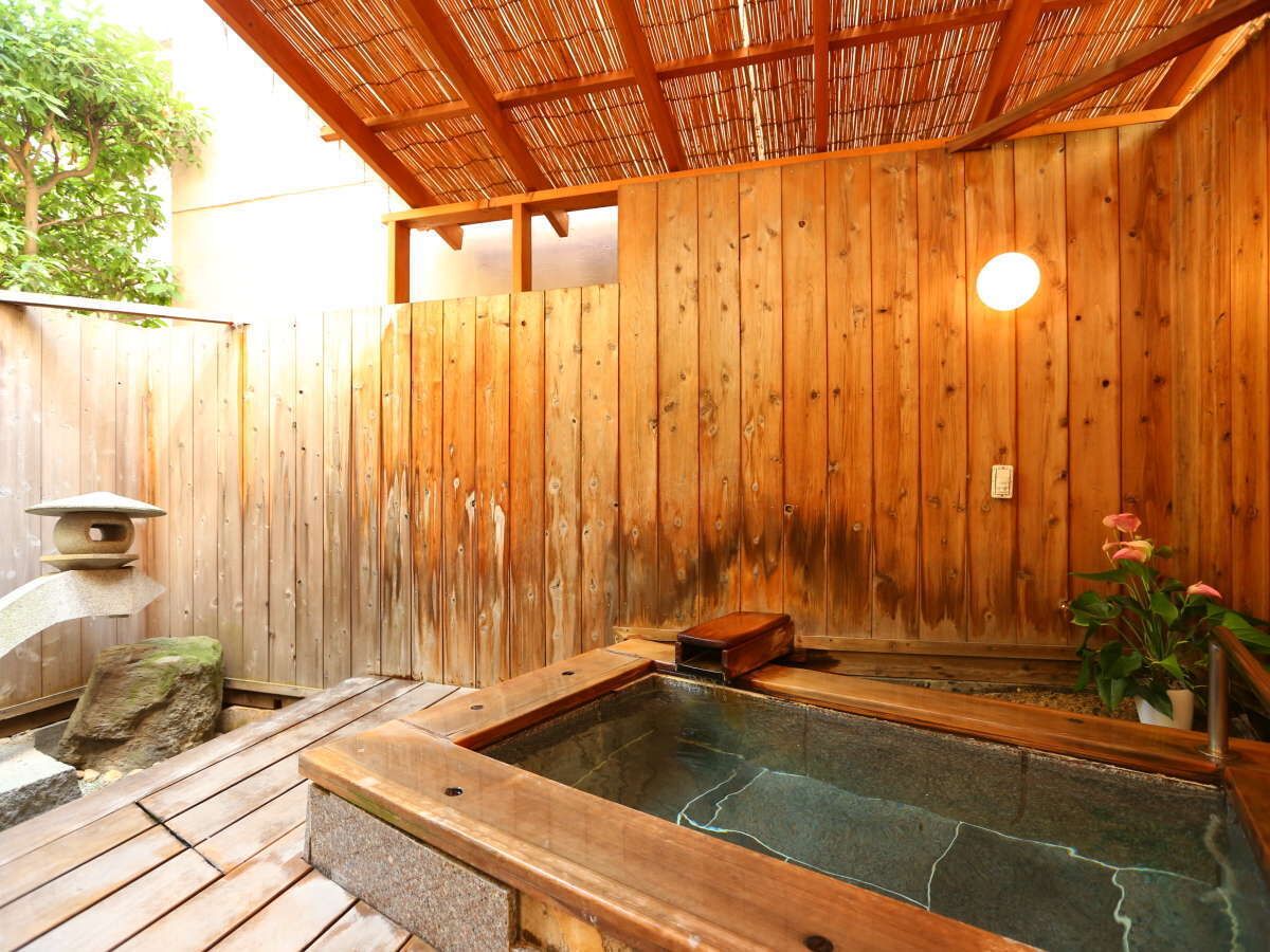 Ein Holz-Wellnessbereich mit Whirlpool, Steinsitzgelegenheiten und einem Holzzaun.