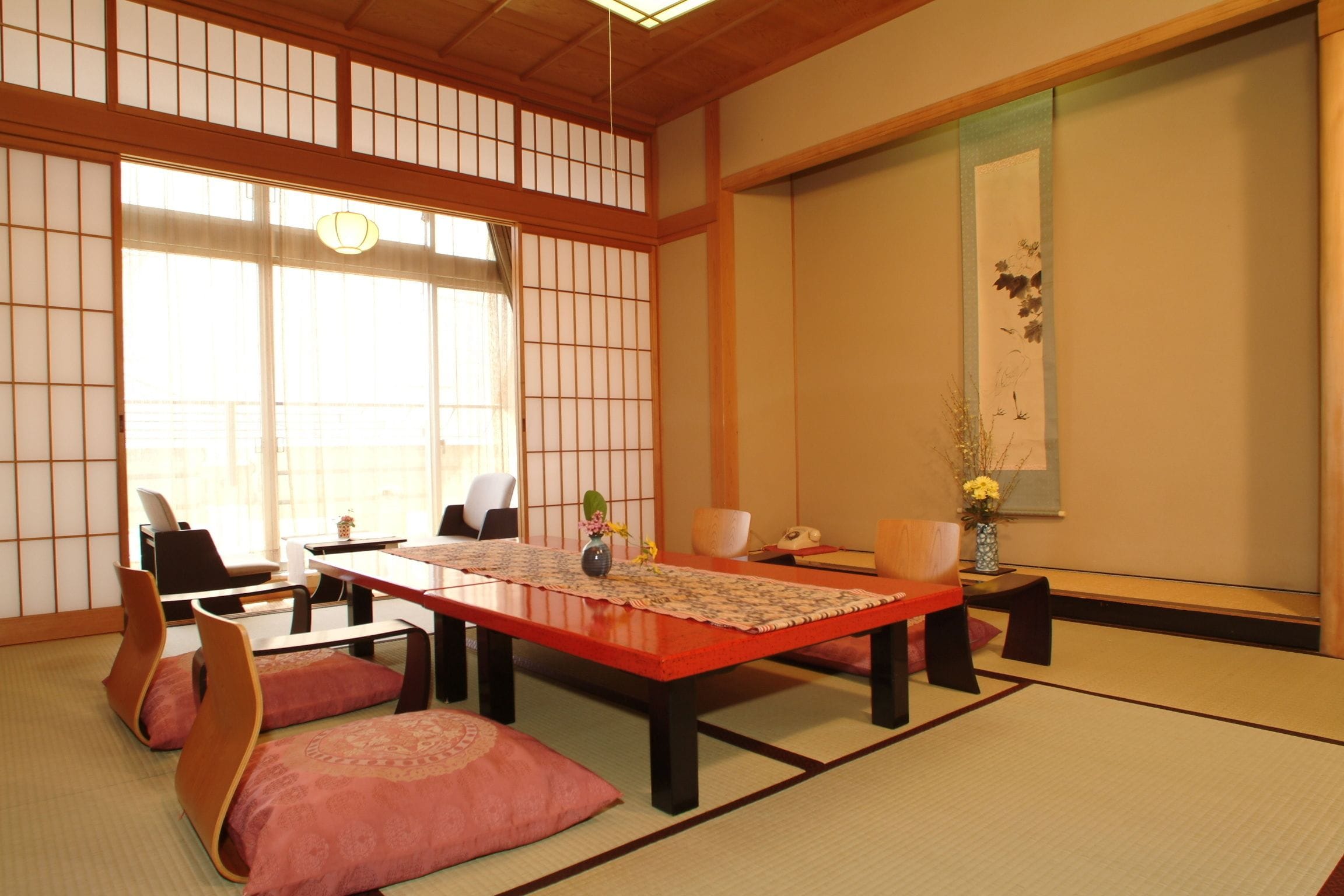 A traditional Japanese room with tatami flooring, a low table with cushions, and sliding doors.
