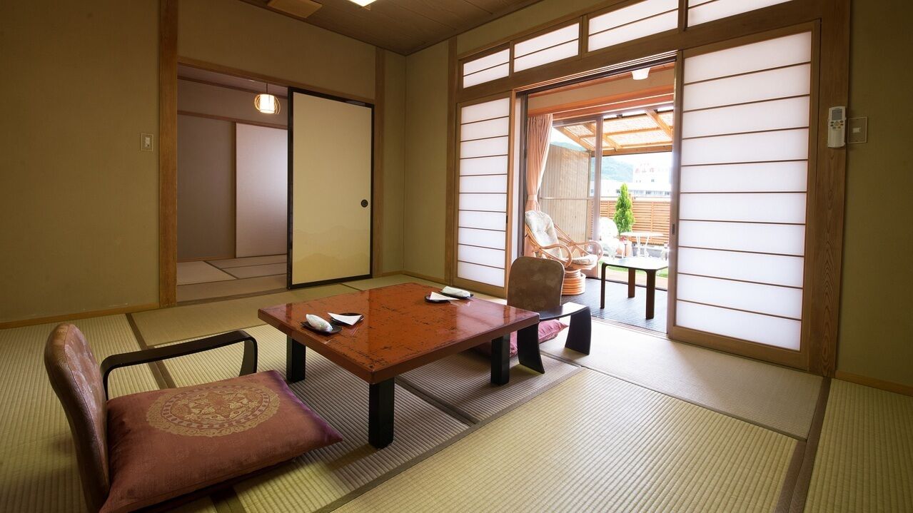 A traditional Japanese room with tatami flooring, a low table, and a cushioned chair.