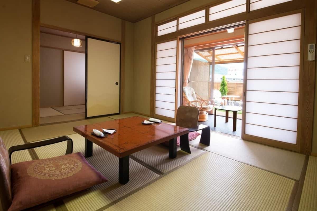 Perinteinen japanilainen huone, jossa on tatamimatto, matala pöytä ja pehmustettu tuoli.