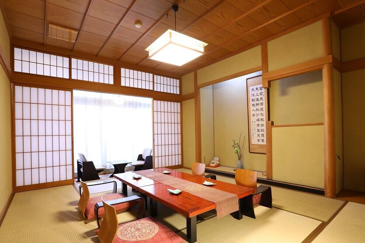 Perinteinen japanilaistyylinen huone, jossa on tatamimatto, matala pöytä tyynyineen ja liukuvat ovet.
