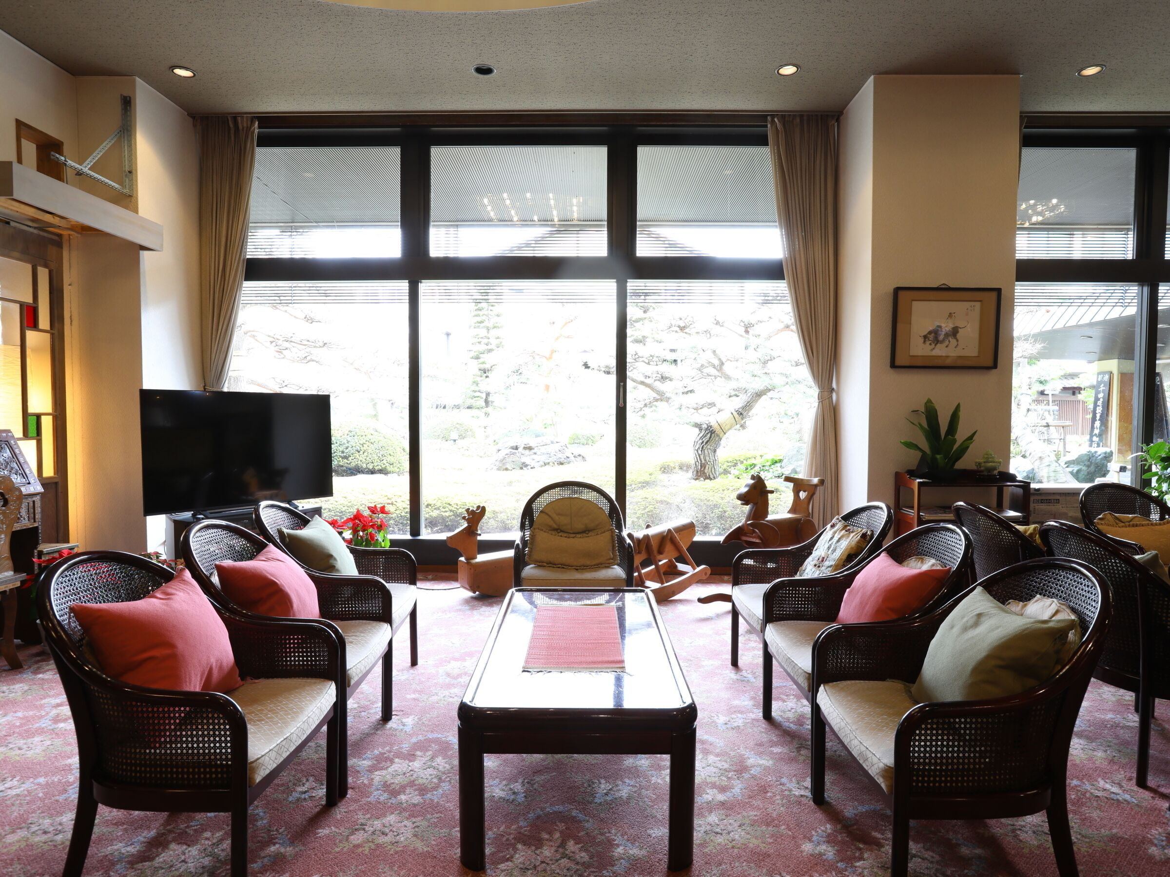 Amplia sala de estar con un ventanal grande, muebles de mimbre, un televisor de pantalla plana y una mesita.