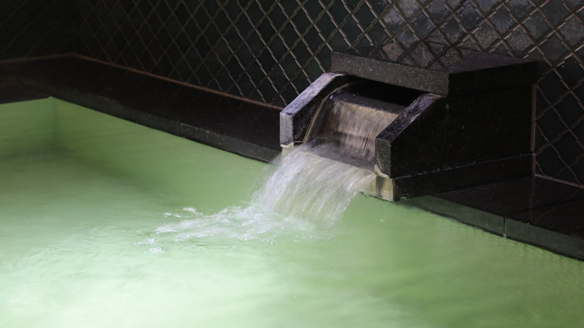 A water feature with a metal grate and a greenish pool.