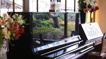 A piano with a view of a garden through a window.