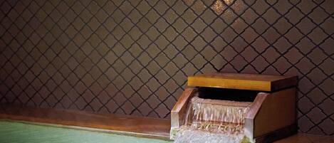 Un pequeño elemento decorativo de madera con un flujo de agua que desemboca en una cuenca verde.