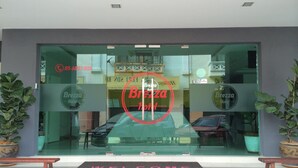 A hotel entrance with a 'Welcome' mat, glass doors, and potted plants. - Brezza Hotel (Lumut)