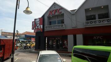A KFC restaurant with a red and white facade, a visible entrance, and a parking sign.