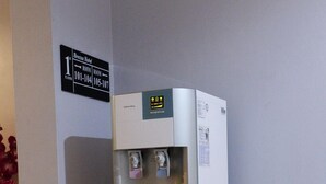 A water dispenser in a hotel lobby with a sign indicating room numbers 101-104 and 105-107. - Brezza Hotel (Lumut)