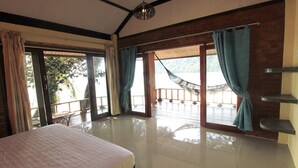 Une chambre spacieuse avec un grand lit et des portes-fenêtres coulissantes donnant sur un balcon équipé d’un hamac.