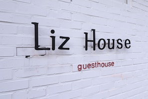 A white brick wall with the text "Liz House" and "guesthouse" in black and red letters. - Liz's House - Hostel (Seoul)