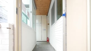 A narrow hallway with a wooden ceiling, white walls, and a fire extinguisher on the right. - Liz's House - Hostel (Seoul)