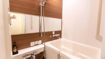 Un baño moderno con una bañera blanca, un mueble de tocador de madera, un espejo y un cabezal de ducha.