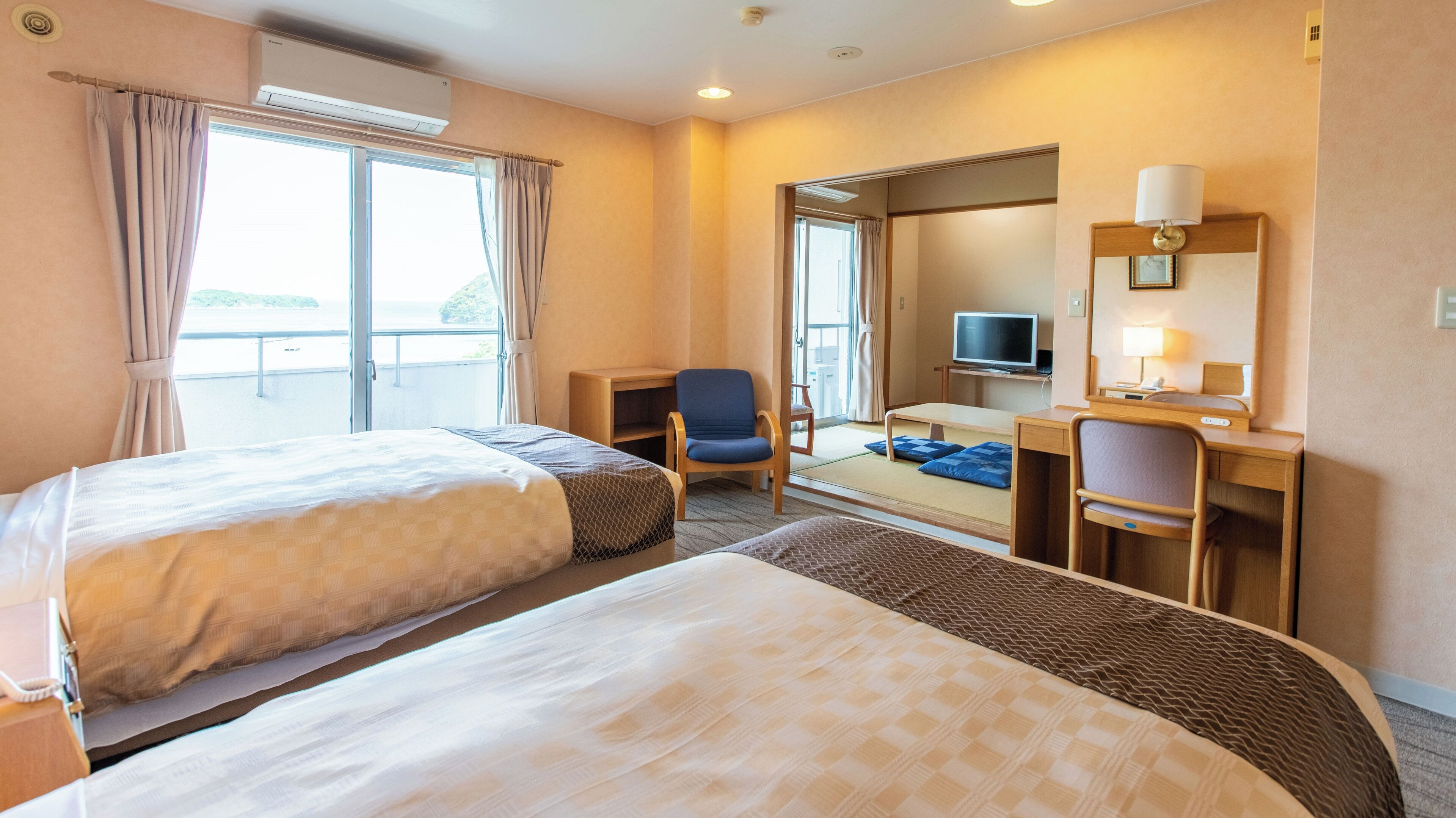 Une chambre d’hôtel avec deux lits, un bureau, une chaise, une télévision et une fenêtre avec des rideaux.