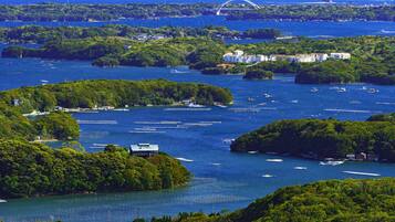 Zona costera con varias islas, barcos y un puente a lo lejos.