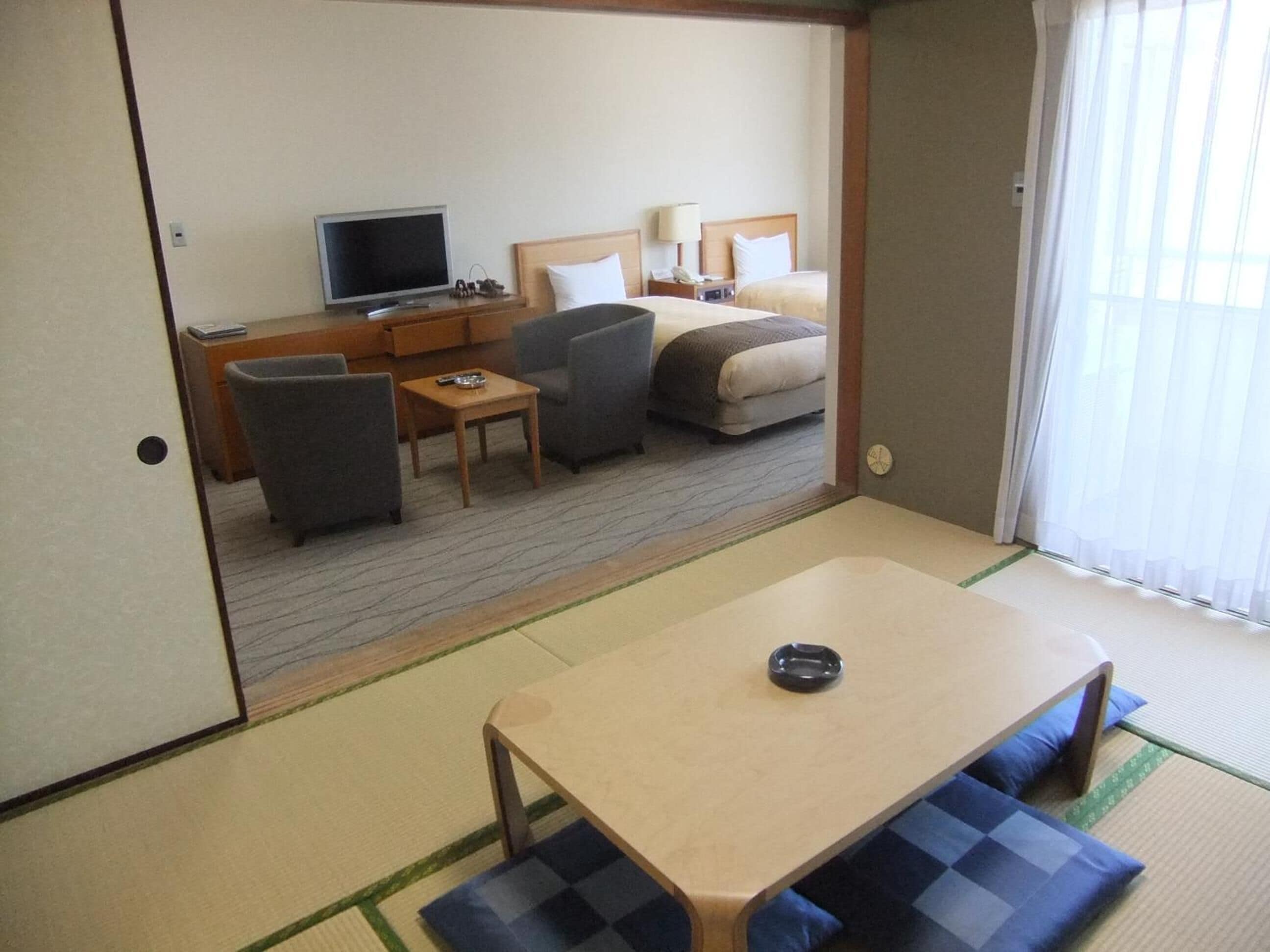 A hotel room with a bed, a desk, a TV, and a dining table.