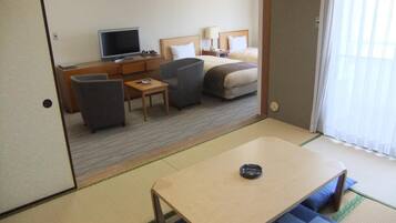 A hotel room with a bed, a desk, a TV, and a dining table.