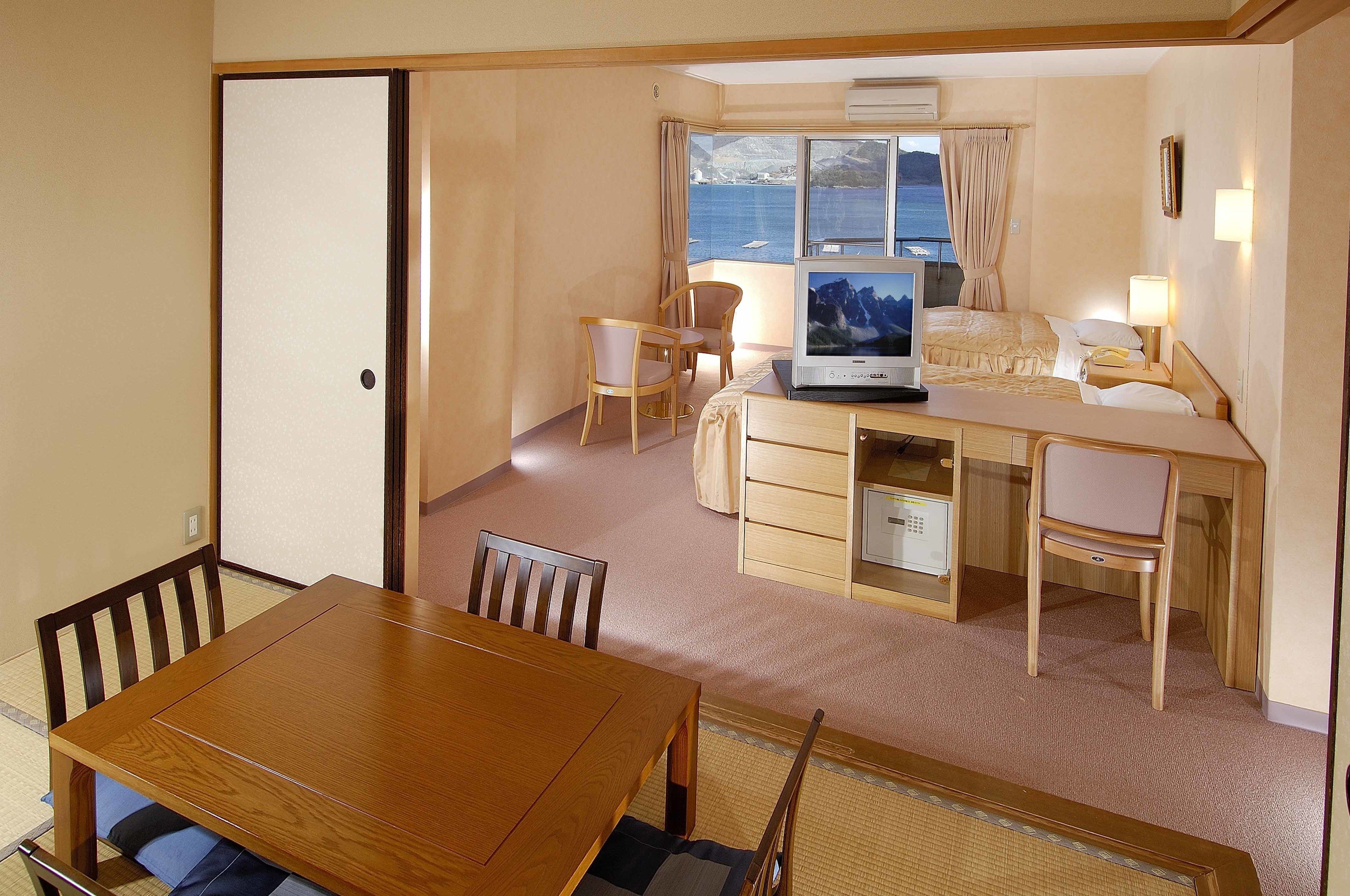 A compact hotel room with a dining area, a bed, a desk, and a television.