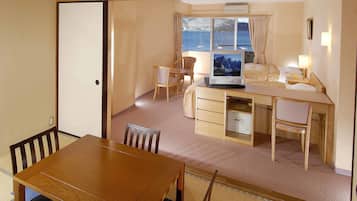 A compact hotel room with a dining area, a bed, a desk, and a television.
