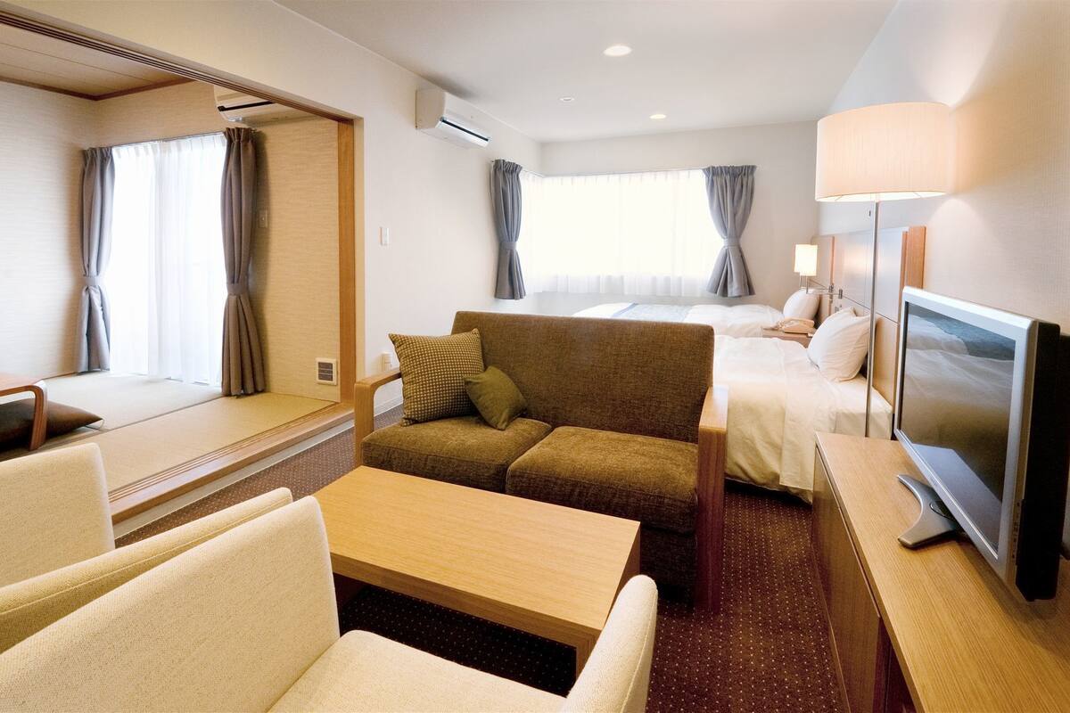 Een hotelkamer met een bank, een bed, een televisie en een bureau.