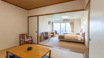 Quarto de hotel com uma mesa de jantar de madeira, um sofá, uma cama e uma escrivaninha.