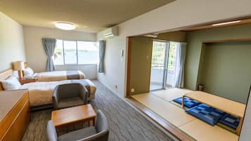 Habitación de hotel con dos camas, un sofá, una mesita y vista al mar.