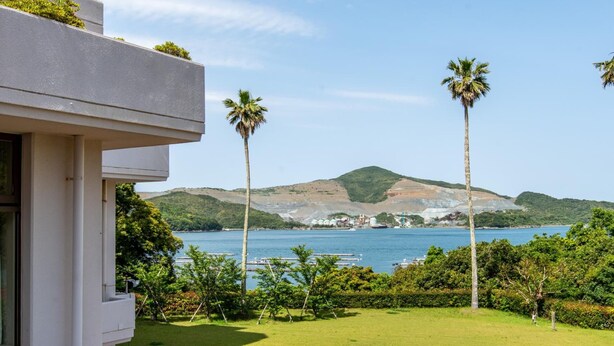 A modern building with a view of a lake and hills.
