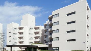 A modern multi-story hotel with a flat facade, balconies, and a covered entrance area.