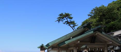 Un edificio japonés tradicional con techo verde, cerca de una costa rocosa.
