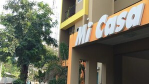 Un edificio con un letrero que dice "Mi Casa" y un pequeño espacio al aire libre con un banco.