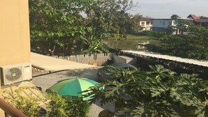 Una zona residencial con un sendero pavimentado, una sombrilla verde y un coche estacionado en la calle.