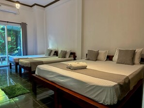 A hotel room with two beds, a large window, and a green mat on the floor.