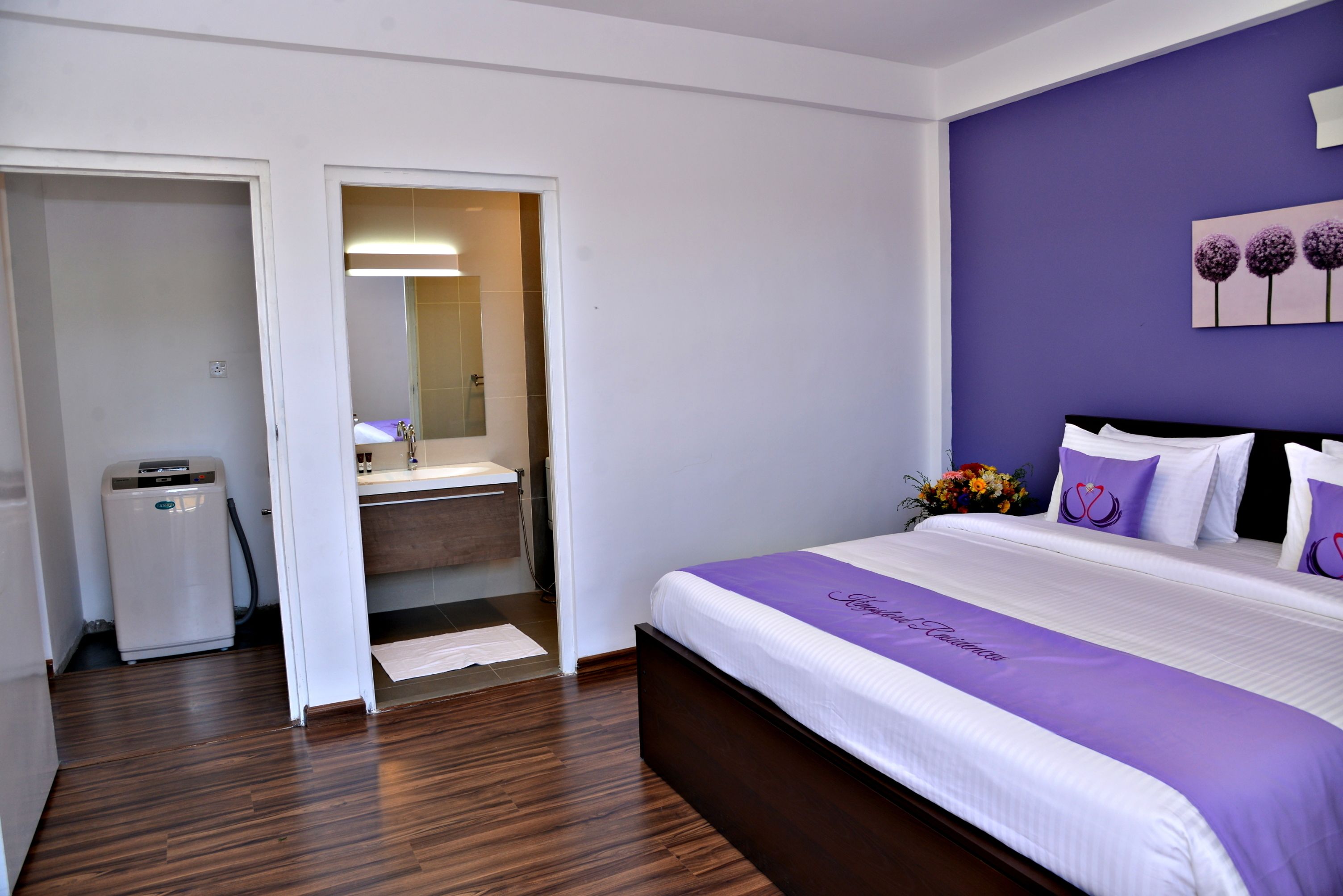 A hotel room with a bed, a bathroom, and a small kitchenette.