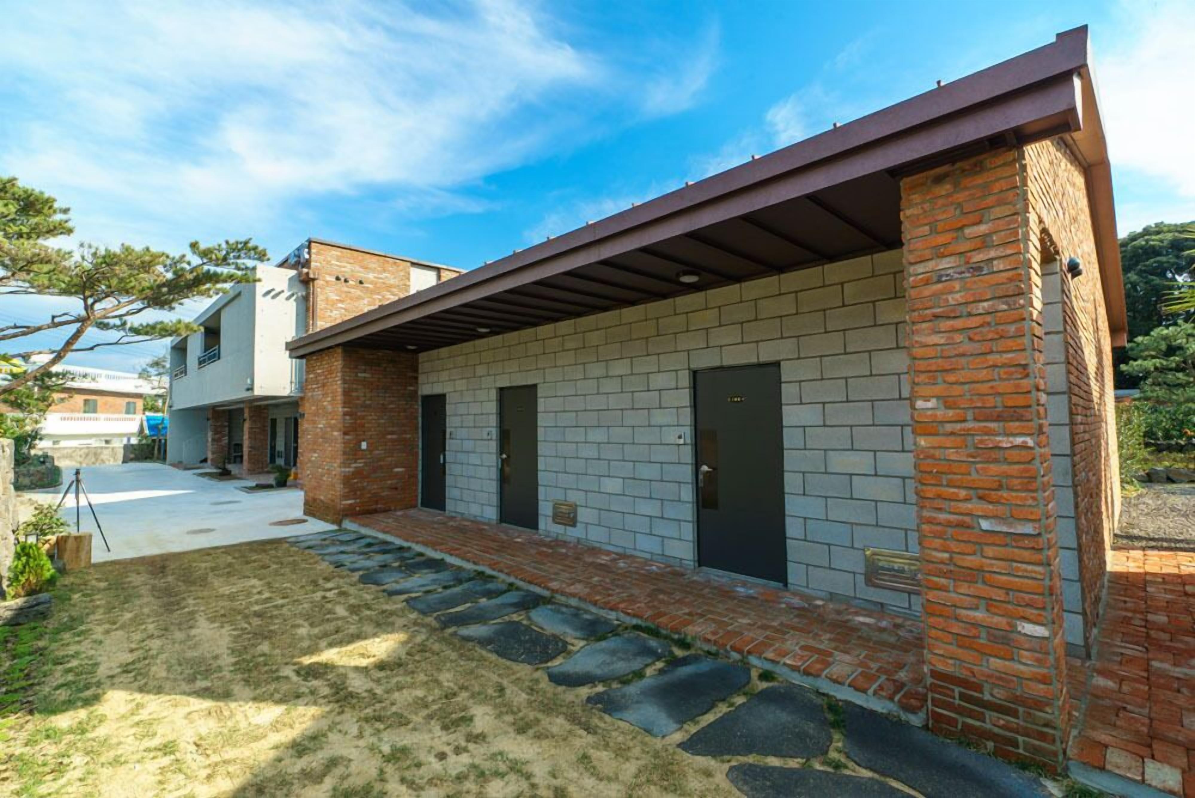 A modern building with a brick facade, a covered walkway, and a clear sky.