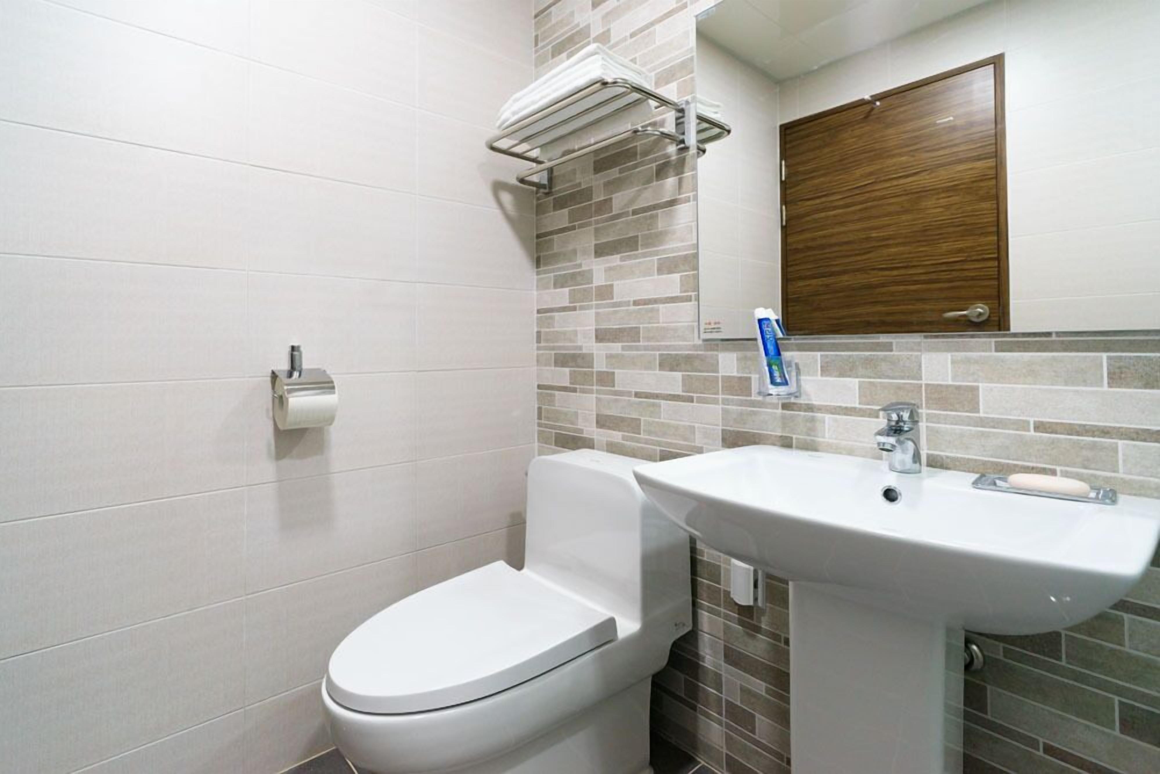 A modern bathroom with a toilet, sink, and a towel rack.