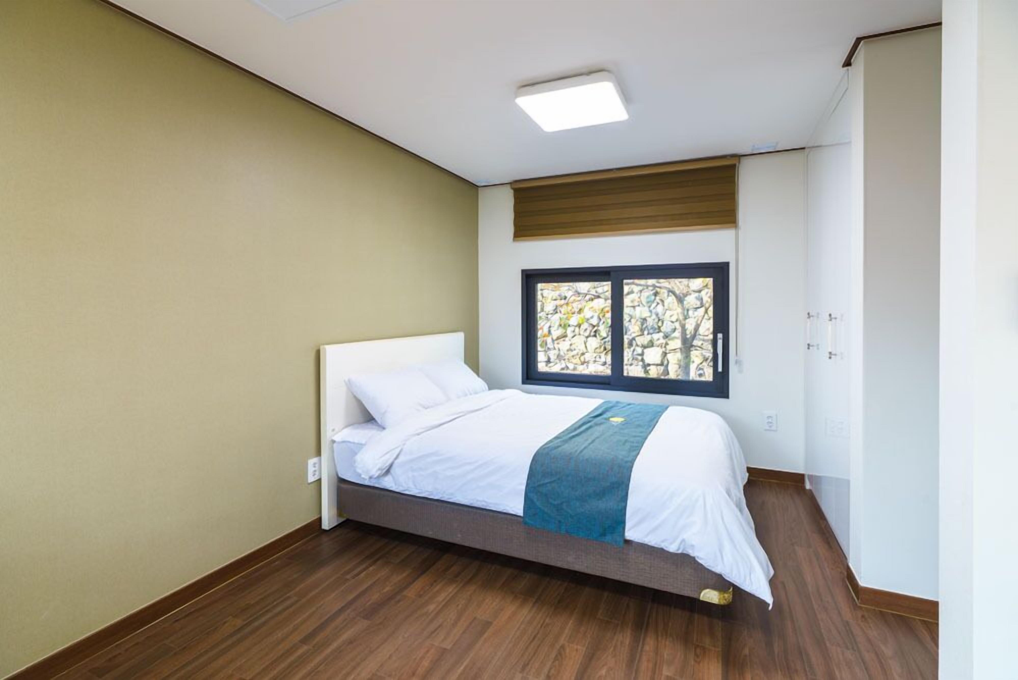 A bedroom with a bed, a window with a view, and a wardrobe.