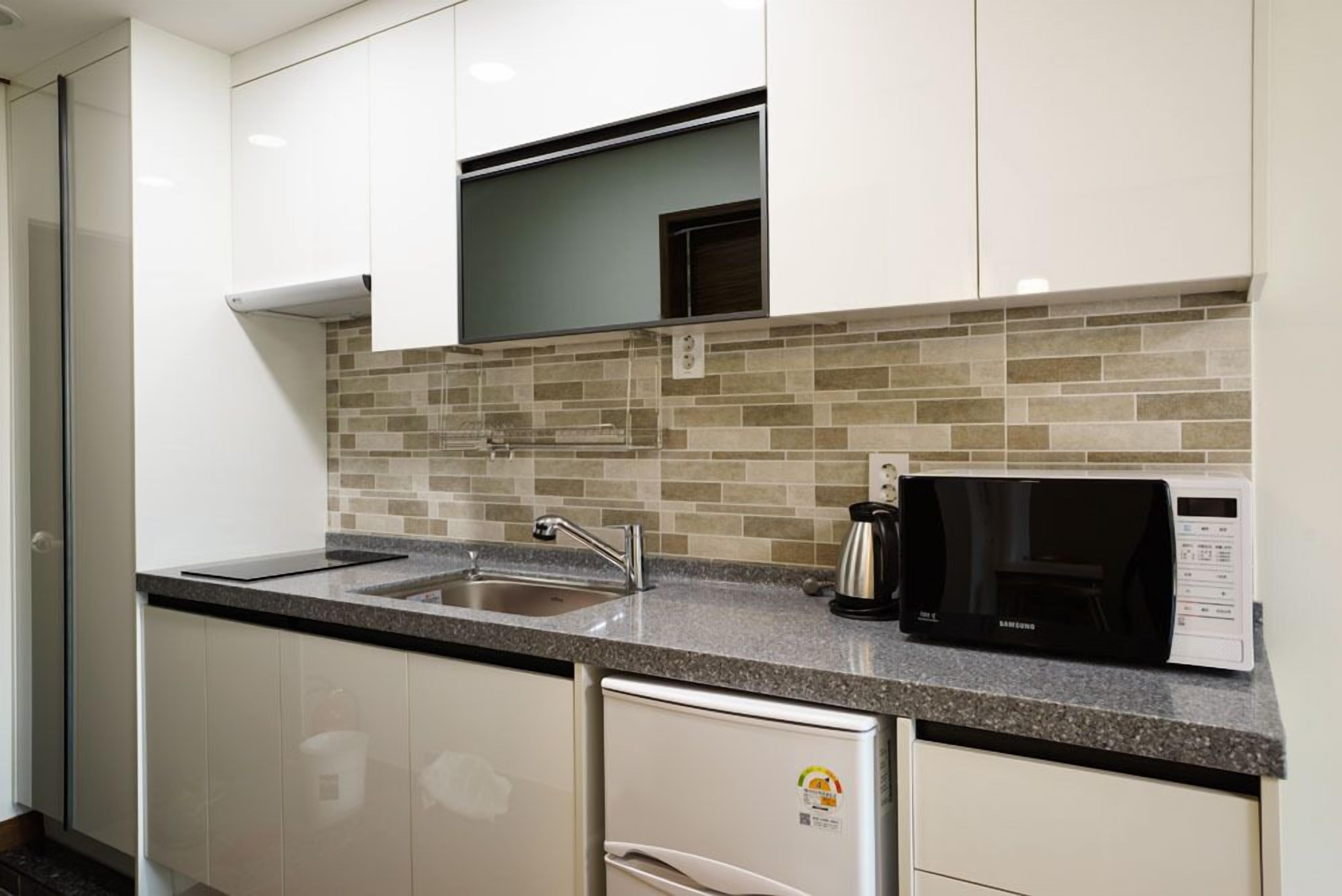A modern kitchen with white cabinets, a granite countertop, a built-in microwave, and a dishwasher.